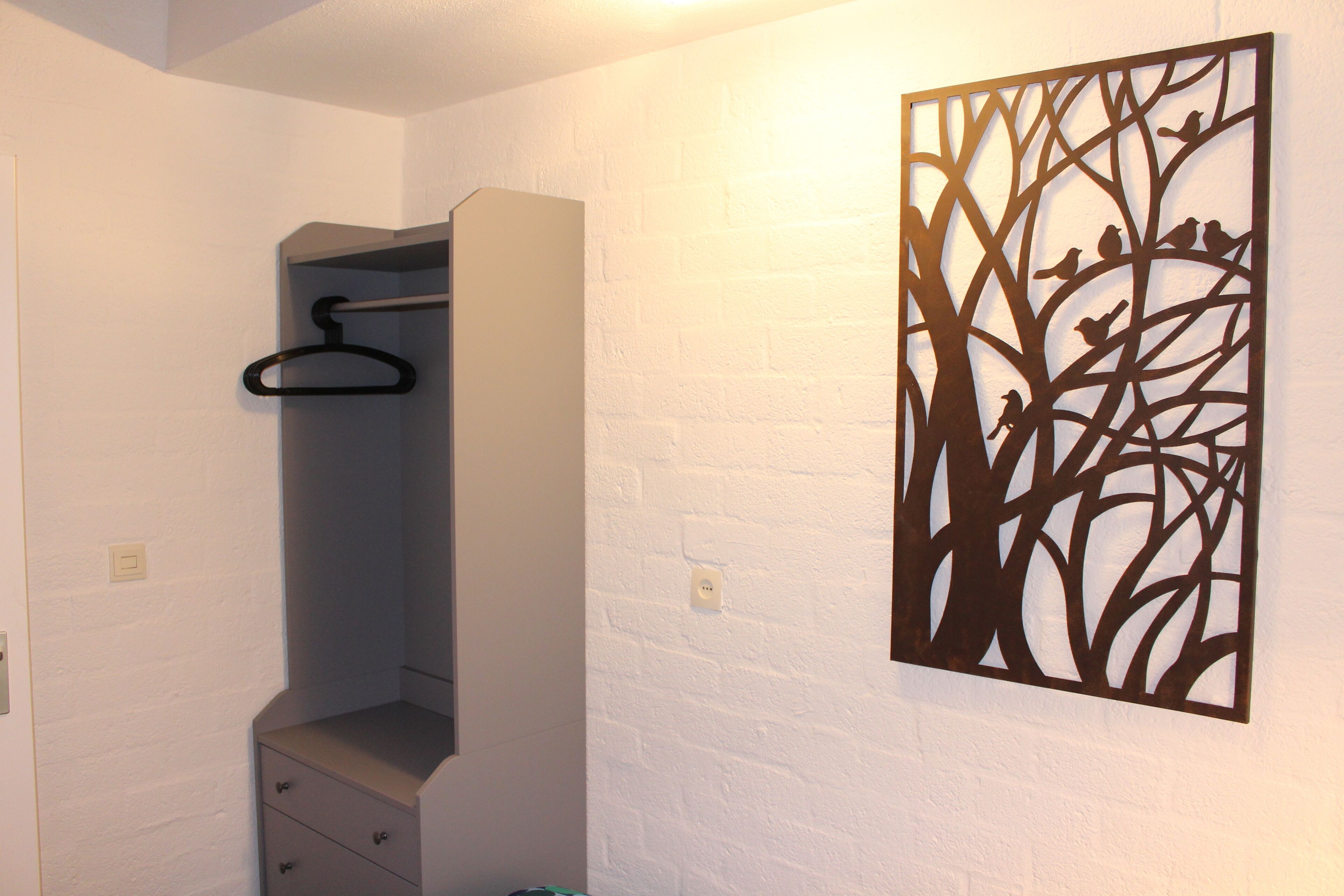 Una habitación con armario, perchero y una obra de arte en la pared.