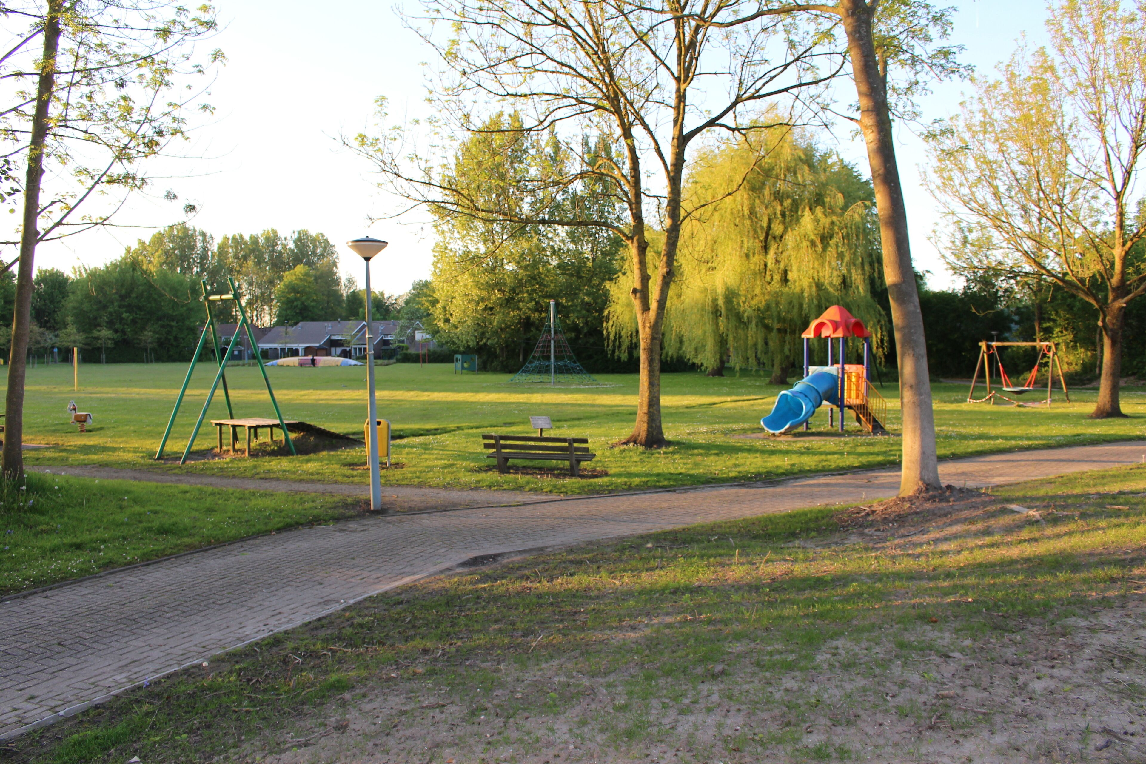 A park with a playground, benches, and a lamp post.