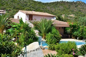 A villa with a swimming pool surrounded by tropical plants and a hillside in the background. - Magnificent villa with sea view (Zonza)