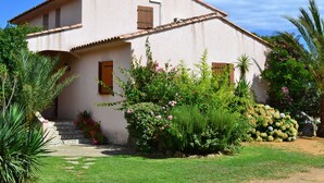 A two-story house with a tiled roof, a stone staircase leading to the entrance, and a well-maintained garden with various plants and flowers. - Magnificent villa with sea view  (Zonza)