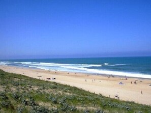 A beach with a clear sky, sandy shore, and a few tents and people. - Large luxury villa T4 1 km from the ocean on the Landes coast  (Messanges)
