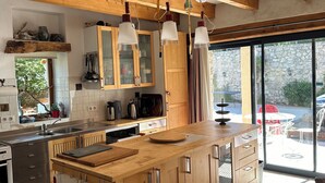 A modern kitchen with wooden cabinetry, a central island, and pendant lighting. - Charming house with swimming pool (Montauban sur l'Ouveze)