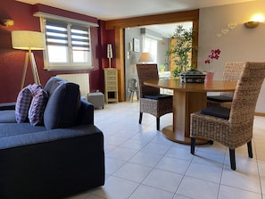 Un salon comprenant un canapé, deux fauteuils en osier, une table à manger et une plante en pot.