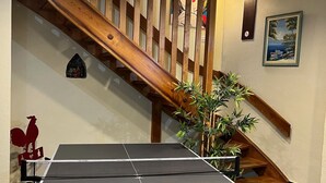 A ping pong table with a wooden staircase in the background.
