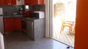 Uma cozinha compacta com armários vermelhos, forno embutido e micro-ondas.