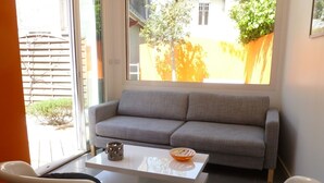 Uma sala de estar moderna com um sofá cinzento, uma mesa de centro branca e duas poltronas brancas.