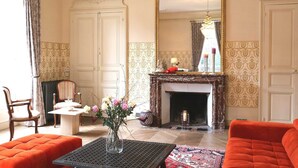 A room with a fireplace, a mirror, and a table with a vase of flowers.