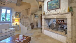 A spacious living room with a fireplace, a staircase, and a view of the outdoors. - Moulin de Villeverneix and its tower, Neuvic on the banks of the Vern for 6, 8 people (Neuvic)