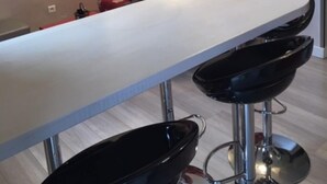 Una cocina moderna con encimera blanca, taburetes negros y un sofá rojo estampado.