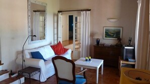 A cozy living room with a white sofa, a wooden chair, a small table, a mirror, and a painting on the wall. - Quiet holiday villa with swimming pool and superb view in the Luberon (Vitrolles-En-Lubéron)