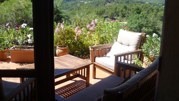 A patio with a wooden table and two chairs, overlooking a lush green landscape. - Quiet holiday villa with swimming pool and superb view in the Luberon (Vitrolles-En-Lubéron)