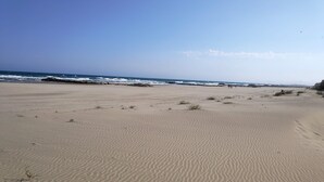 A wide sandy beach with gentle waves and a clear sky.