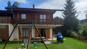 Una casa de madera con balcón, un columpio y un porche cubierto.