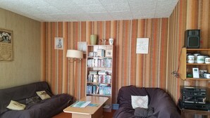 Een woonkamer met twee banken, een salontafel, een boekenkast en een muur met gestreept behang.