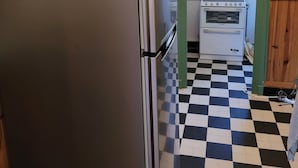 Een keuken met een koelkast, oven en een geruit vloertje.