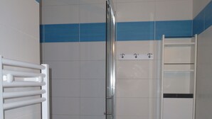A bathroom with a glass shower enclosure, a white sink, and a towel rack.