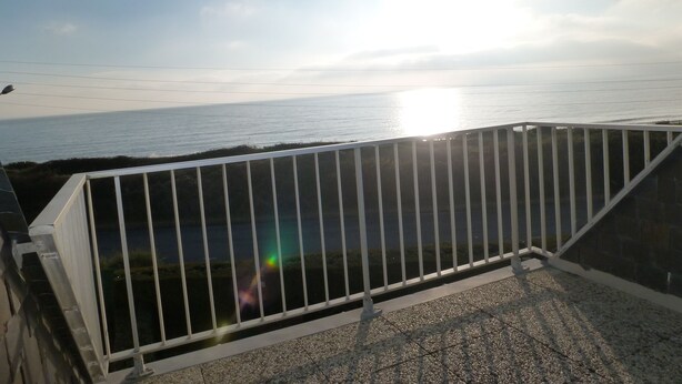 A balcony with a metal railing overlooking a body of water.