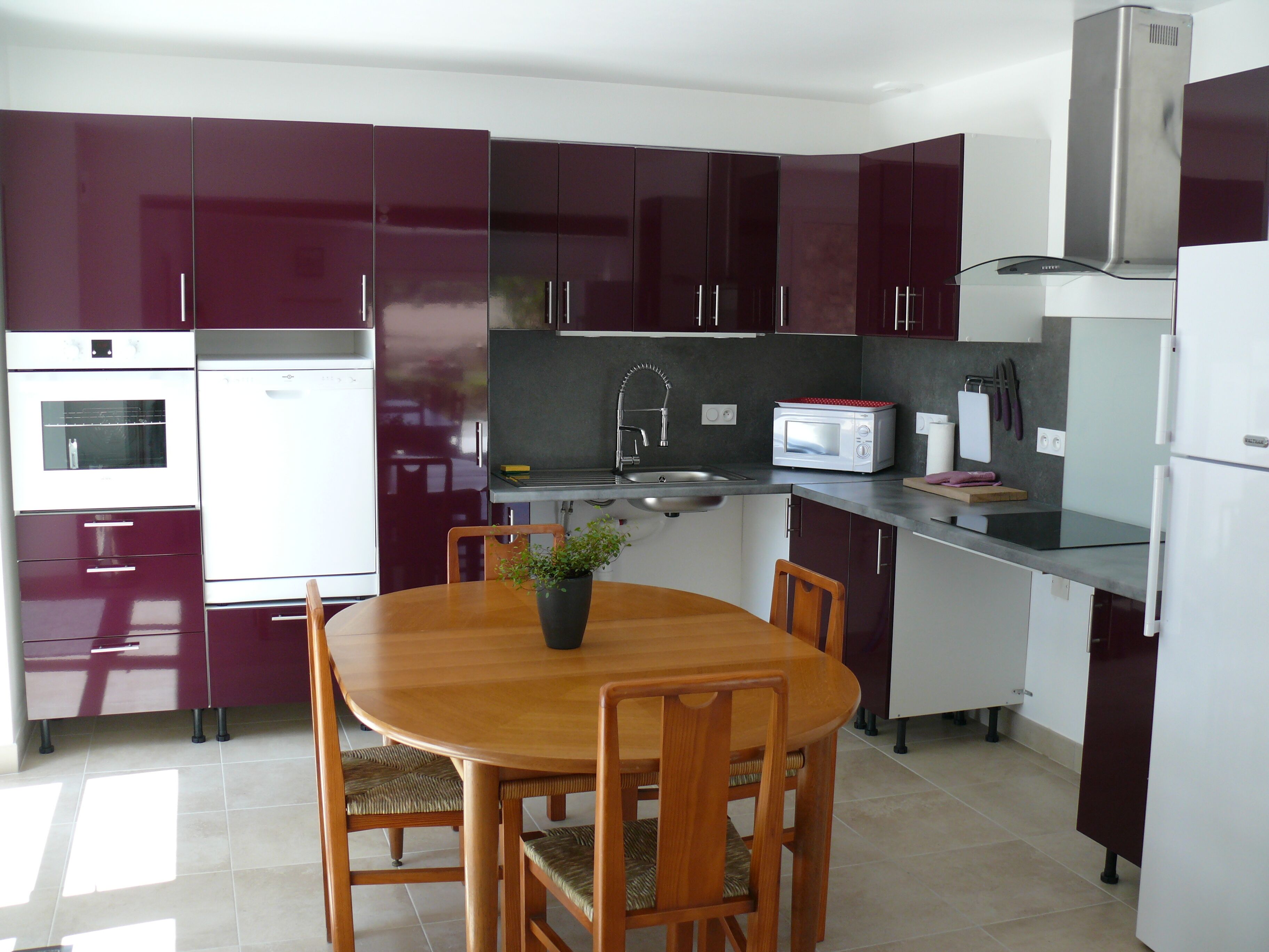 Una cocina moderna con armarios oscuros, una mesa de comedor de madera y electrodomésticos básicos.