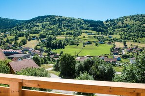 A scenic view of a village with houses and green fields, viewed from a wooden balcony. - La Bresse Spacious And Comfortable Chalet (La Bresse)