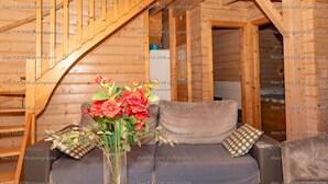 A wooden cabin interior with a staircase, a sofa, and a vase of flowers. - La Bresse Spacious And Comfortable Chalet (La Bresse)