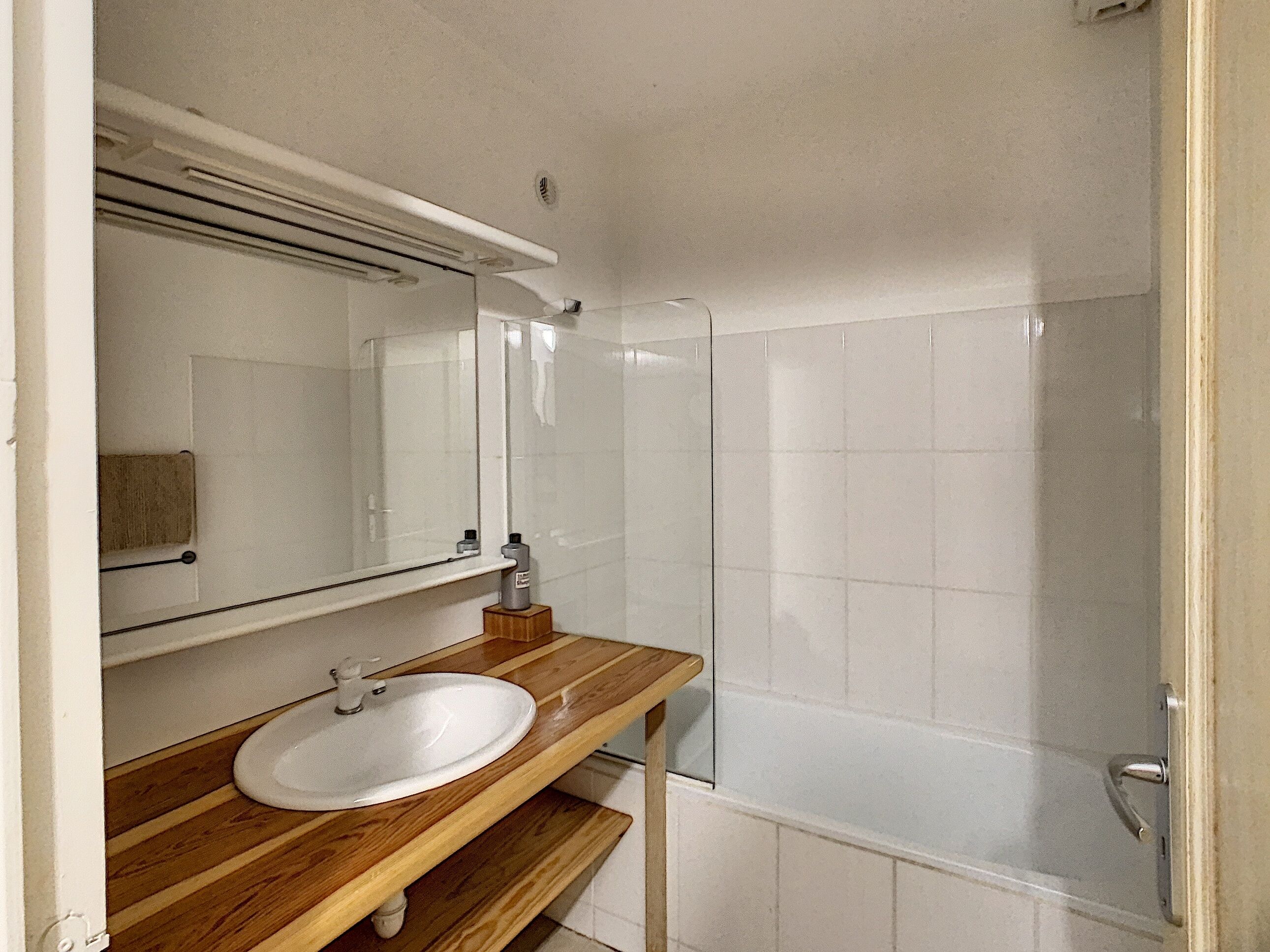 Ein Badezimmer mit Holzwaschtisch, einem weißen Waschbecken und einer Duschkabine aus Glas.