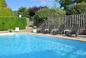 A swimming pool with lounge chairs and a wooden fence. - House - secure heated swimming pool - barbecue - plancha - free wifi (Ispagnac)