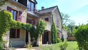 Ein zweistöckiges Haus mit Balkon, Efeu bewachsene Wände und einer Stein Fassade.