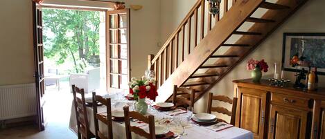 Un comedor con una escalera de madera, una mesa dispuesta para comer y vistas al exterior.