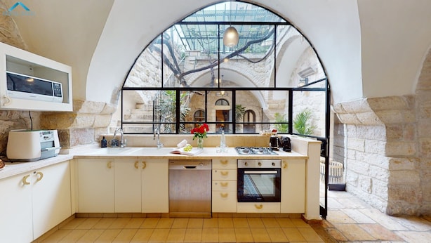 A kitchen with a large arched window, a built-in microwave, a sink, and a stove.