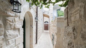 A narrow stone alleyway with arched doorways, a lantern, and a building entrance.