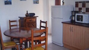 A compact kitchen with a dining table, chairs, a refrigerator, and a microwave. - Apartment of 72 m2 in a house in Corsica (Olmeto)