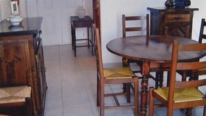 A dining area with a round wooden table and four chairs, each with a cushioned seat. - Apartment of 72 m2 in a house in Corsica (Olmeto)