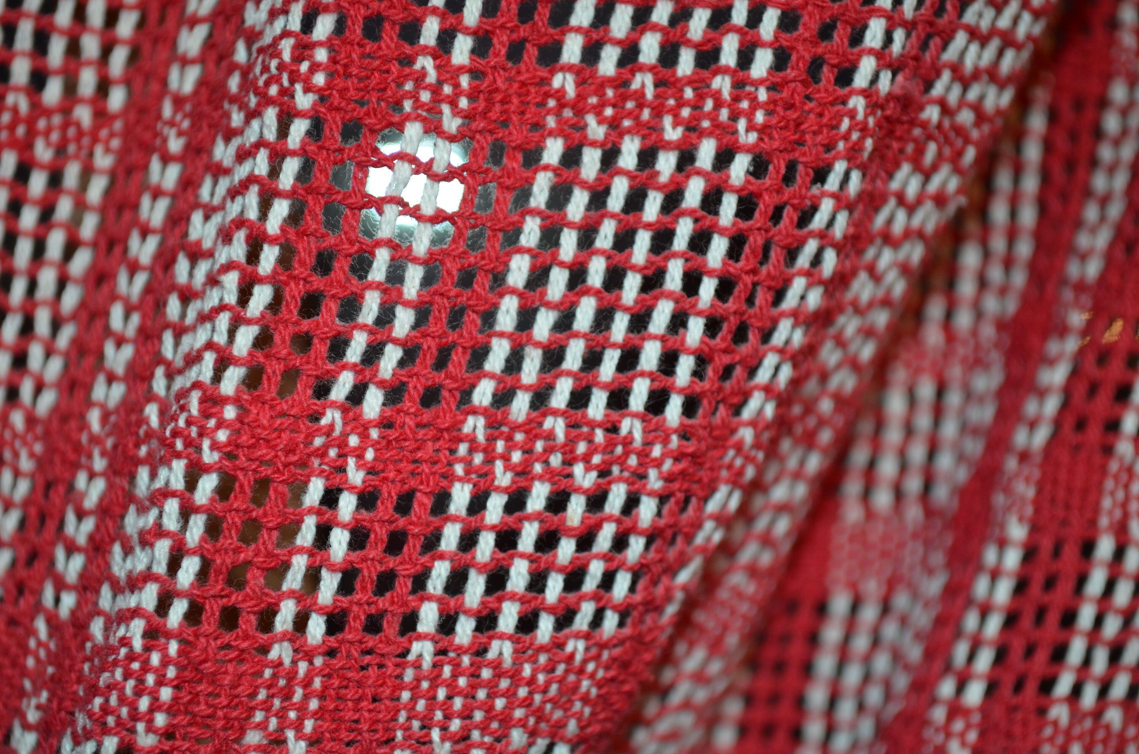 A close-up of a red and white checkered fabric with a hole.