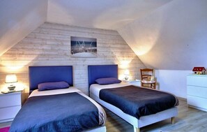 A bedroom with two beds, wooden slat walls, and a picture above the beds.