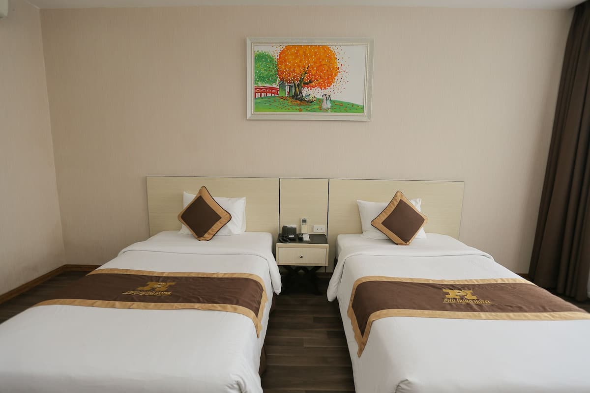 Een hotelkamer met twee bedden, een nachtkastje en een schilderij aan de muur.