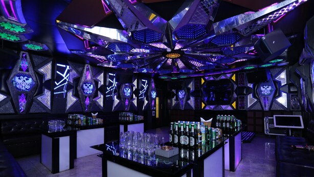 A bar area with multiple bar counters, shelves of bottles, and glasses. - Central Phu Hung Hotel (Quang Phu)