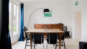 Ein Essbereich mit einem Holztisch, schwarzen Stühlen, einer schwarzen Stehlampe und einem Holzschrank.