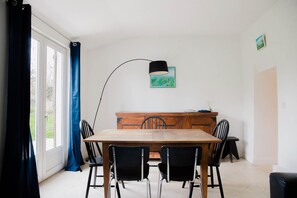 Un coin repas comprenant une table en bois, des chaises noires, un lampadaire noir et un meuble en bois.