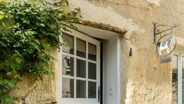 Ein Gebäude mit einer weißen Tür, einem kleinen Fenster und einem Schild mit einer Kuh.