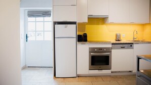 A kitchen with white cabinets, a yellow backsplash, a built-in oven, and a dishwasher. - Le Cottage - Ferme de Pontaly (BAILLY)