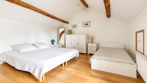 Quarto com duas camas, cómoda, espelho e radiador.