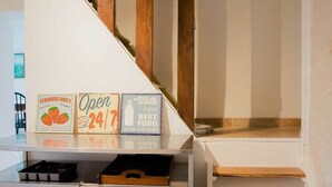 Eine Treppe mit Holzstufen und einer weißen Wand. Auf der Wand befinden sich Schilder, die 'Erdbeeren' und 'geöffnet 24 Stunden' bewerben.