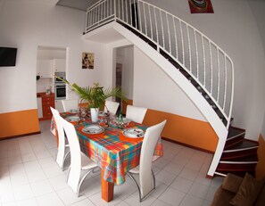 A dining area with a colorful tablecloth, white chairs, and a white staircase. - Etal Paradise, a Tropical Paradise in Sainte-Anne in Guadeloupe (SAINTE ANNE)