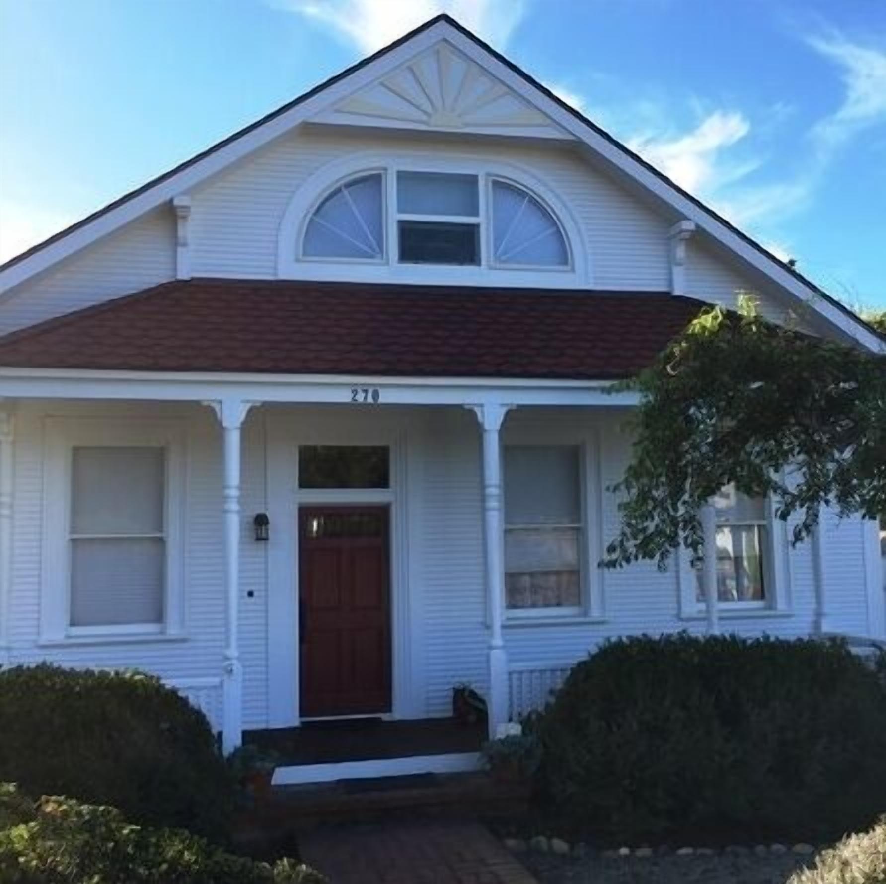 A two-story white house with a brown roof, a front porch, and a number '270' on the front door.