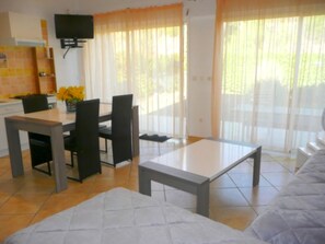 A modern living room with a sofa, a coffee table, and a dining area with a table and chairs.