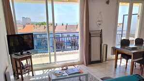 Habitación de hotel con cama, televisión, balcón con vistas, mesa y una silla.