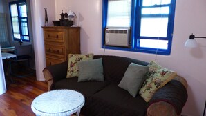 Un salon chaleureux avec un canapé marron foncé, des coussins à motifs floraux, une petite table blanche et un meuble en bois.