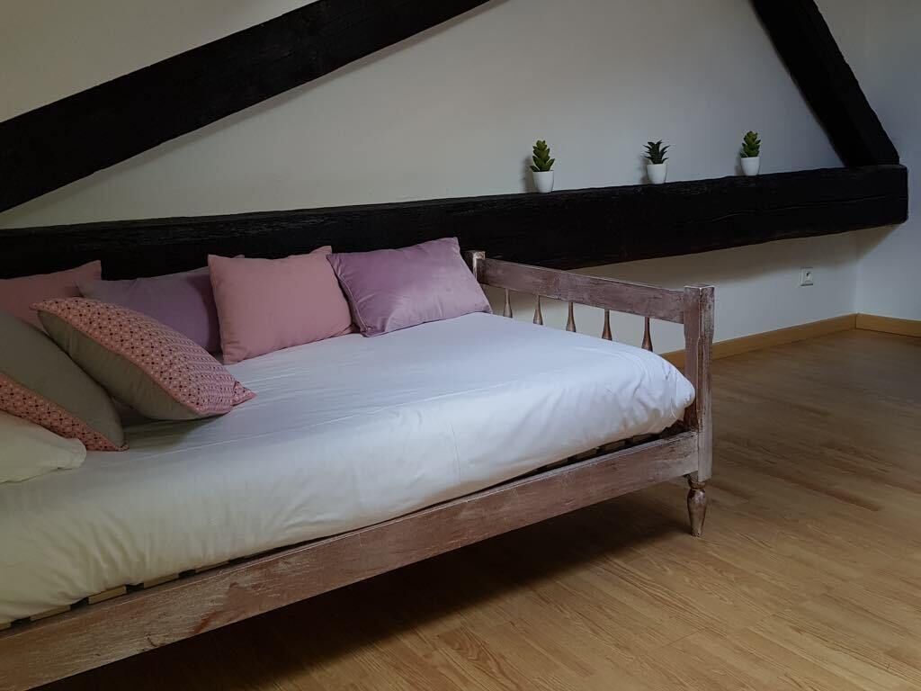 Un dormitorio con cama de madera, ropa de cama blanca y techo inclinado.