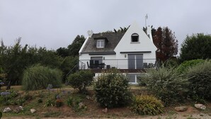 Een wit huis met een schuin dak, een schotelantenne en een klein raam.