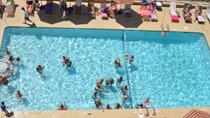 A swimming pool with multiple lanes, lounge chairs, and umbrellas.